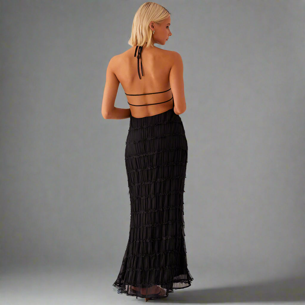 Woman wearing a black dress with cut-out back on a white background