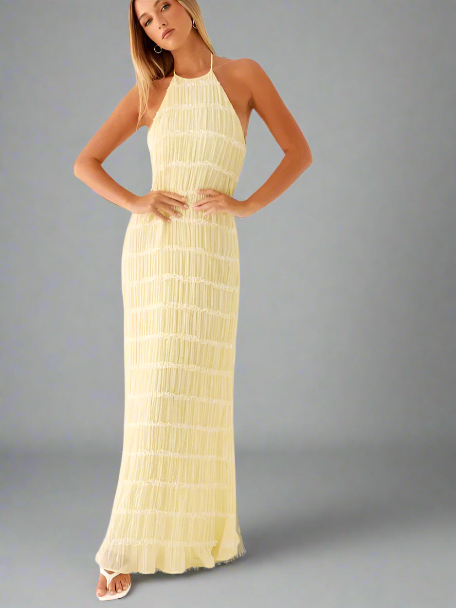 Woman wearing a yellow halter neck dress on a white background